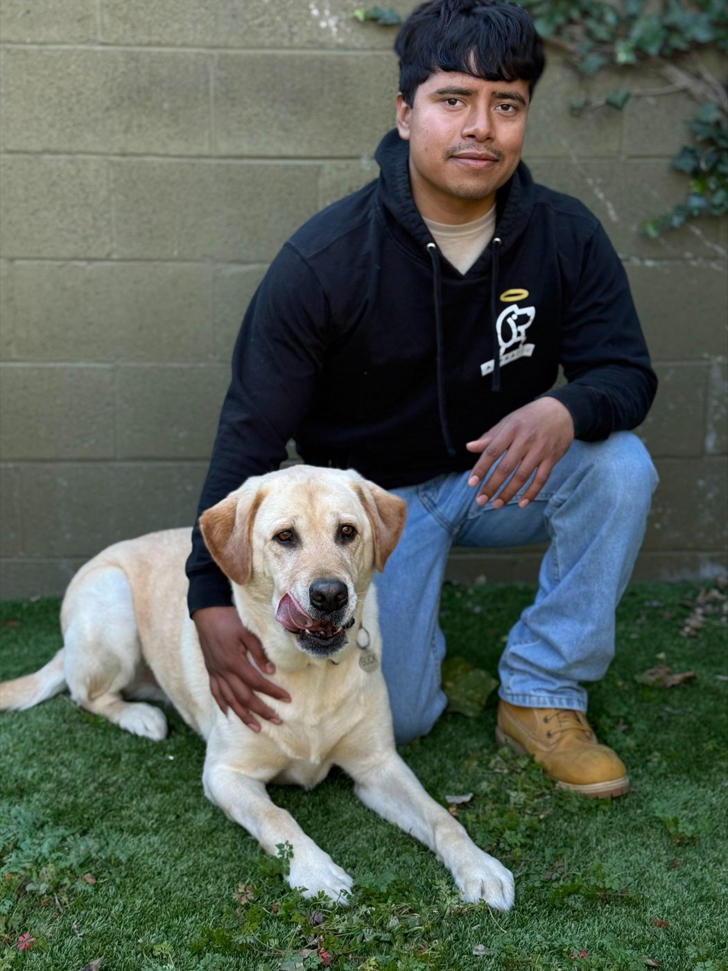 An AlphaDog team member with a dog in the yard