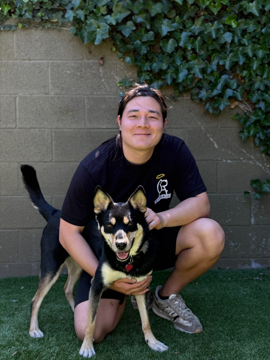 An AlphaDog team member with a dog in the yard