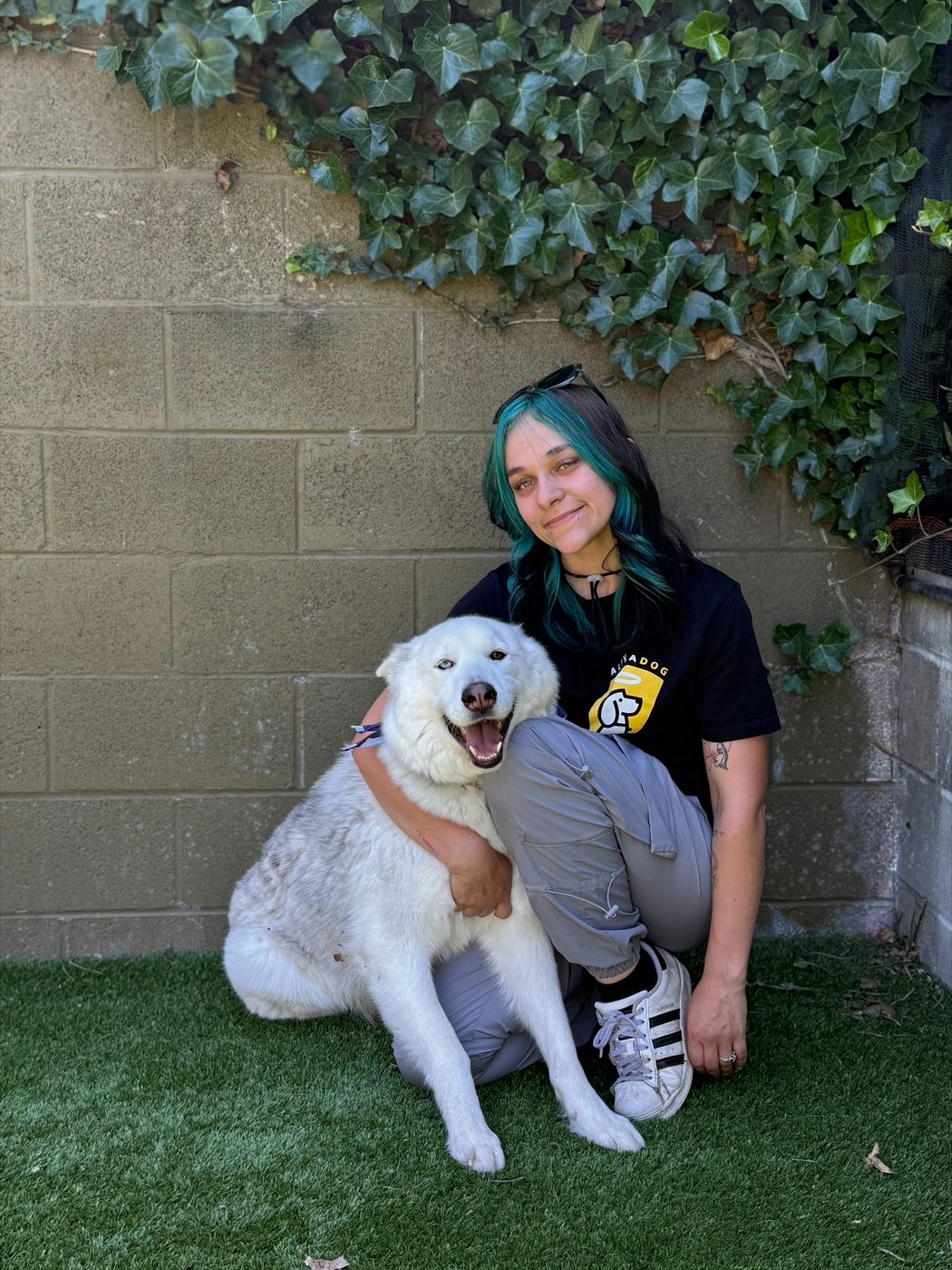 An AlphaDog team member with a dog in the yard
