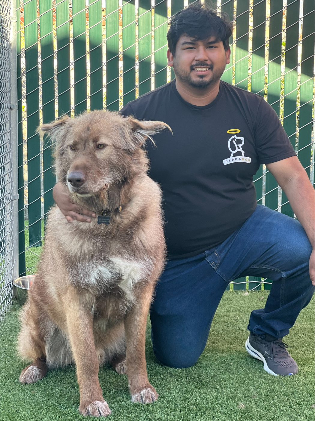 An AlphaDog team member with a dog in the yard