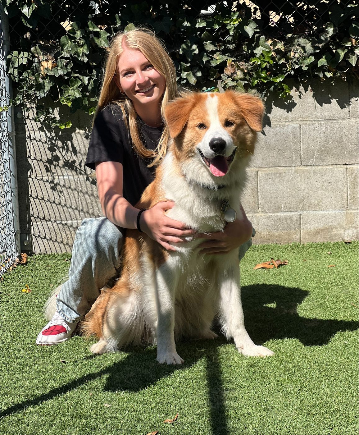 An AlphaDog team member with a dog in the yard