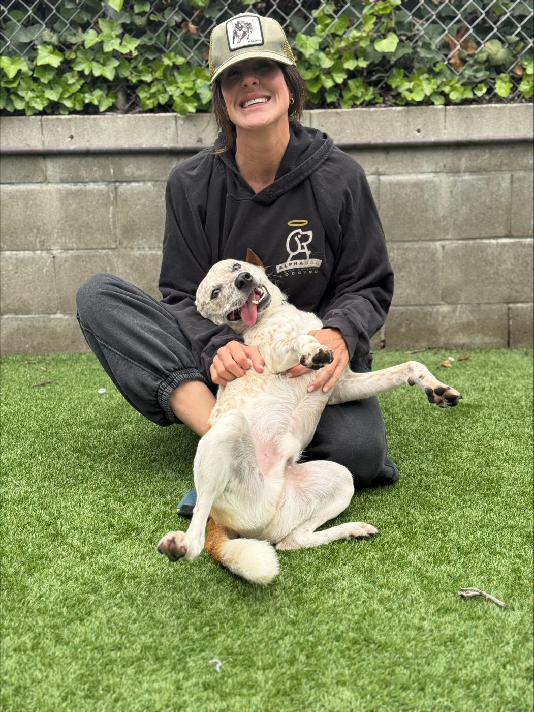 An AlphaDog team member with a dog in the yard