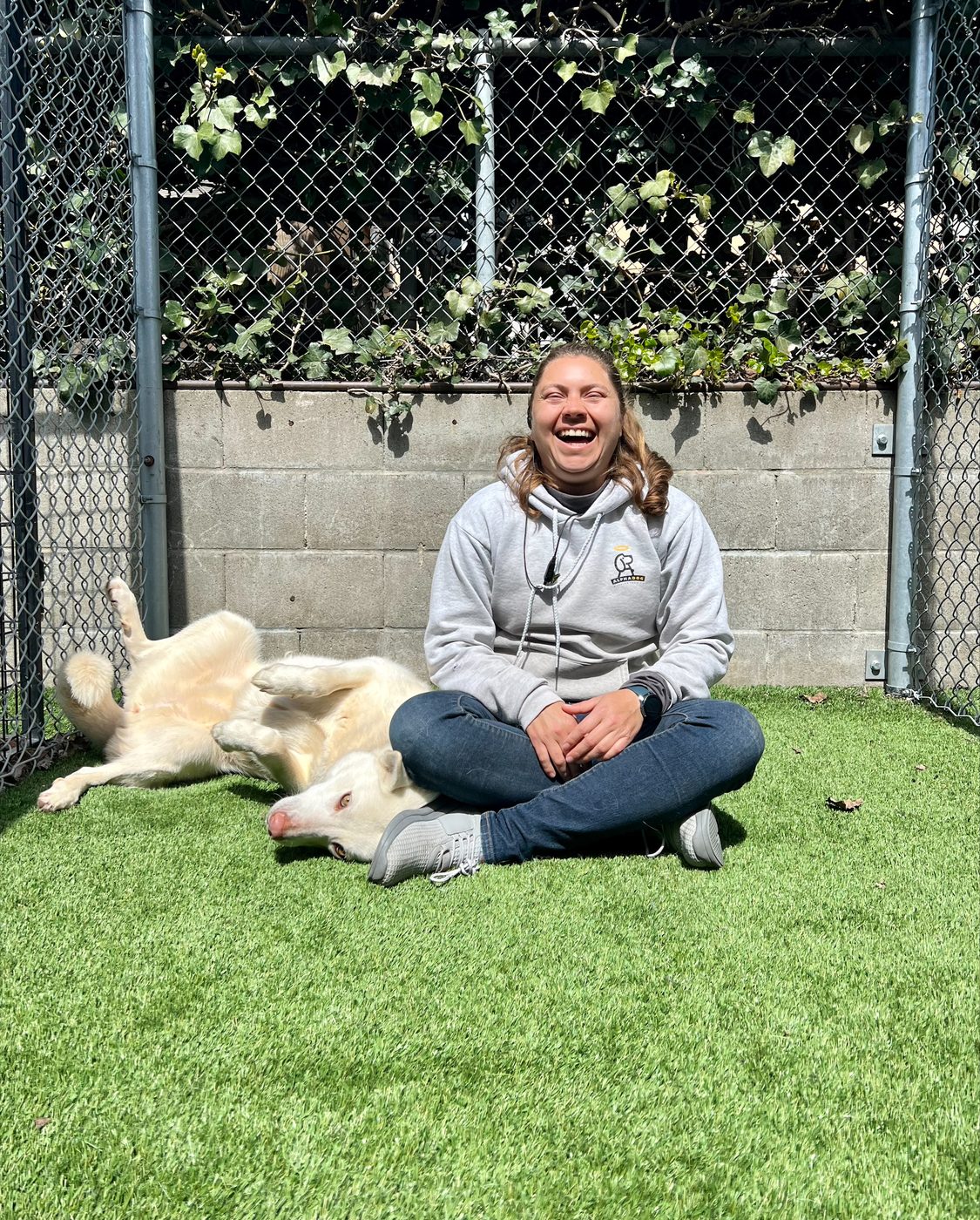 An AlphaDog team member with a dog in the yard
