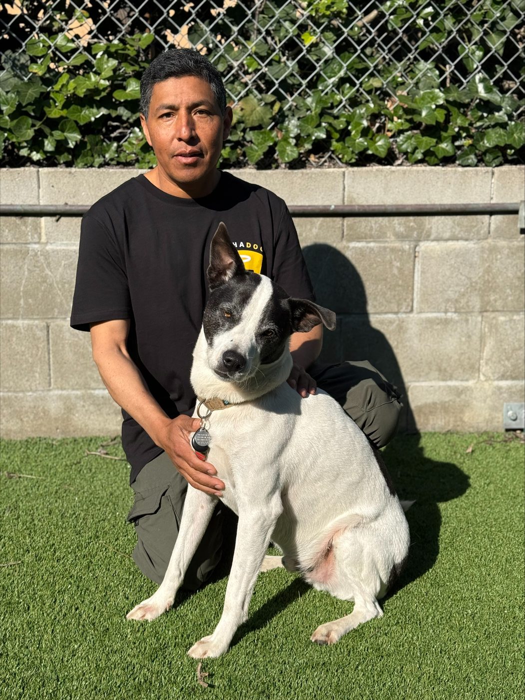 An AlphaDog team member with a dog in the yard