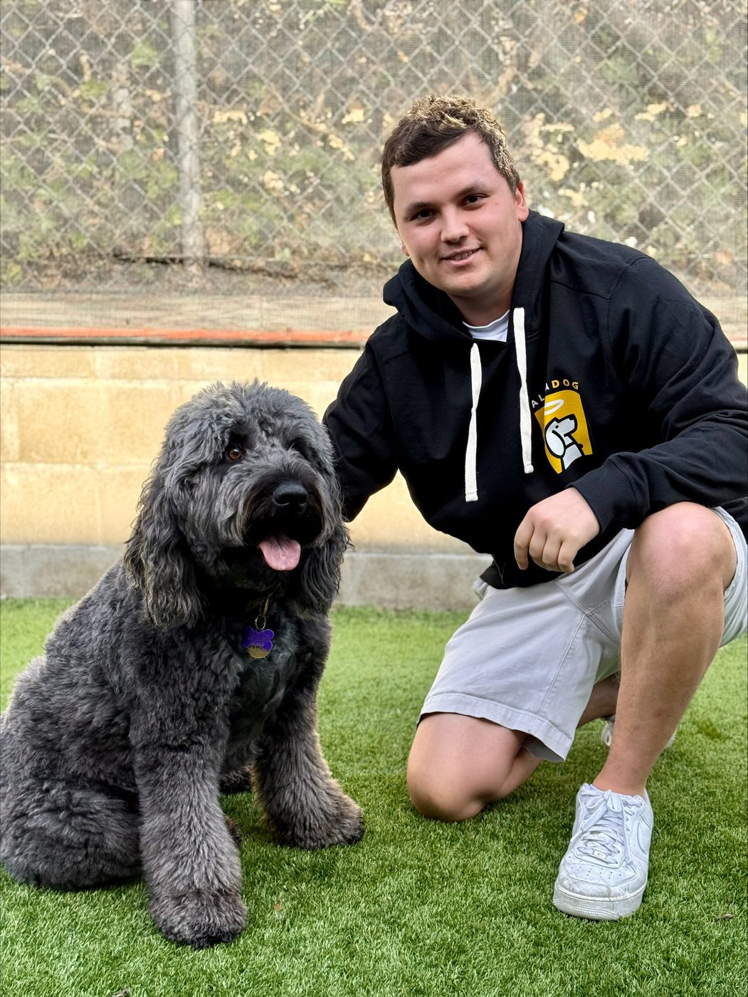 An AlphaDog team member with a dog in the yard