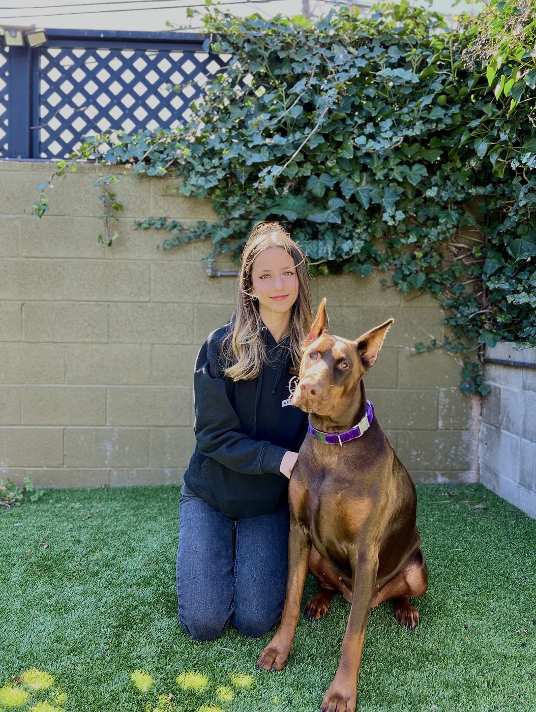 An AlphaDog team member with a dog in the yard