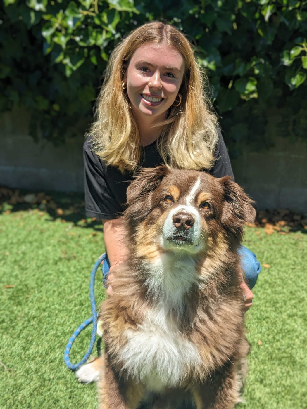 An AlphaDog team member with a dog in the yard