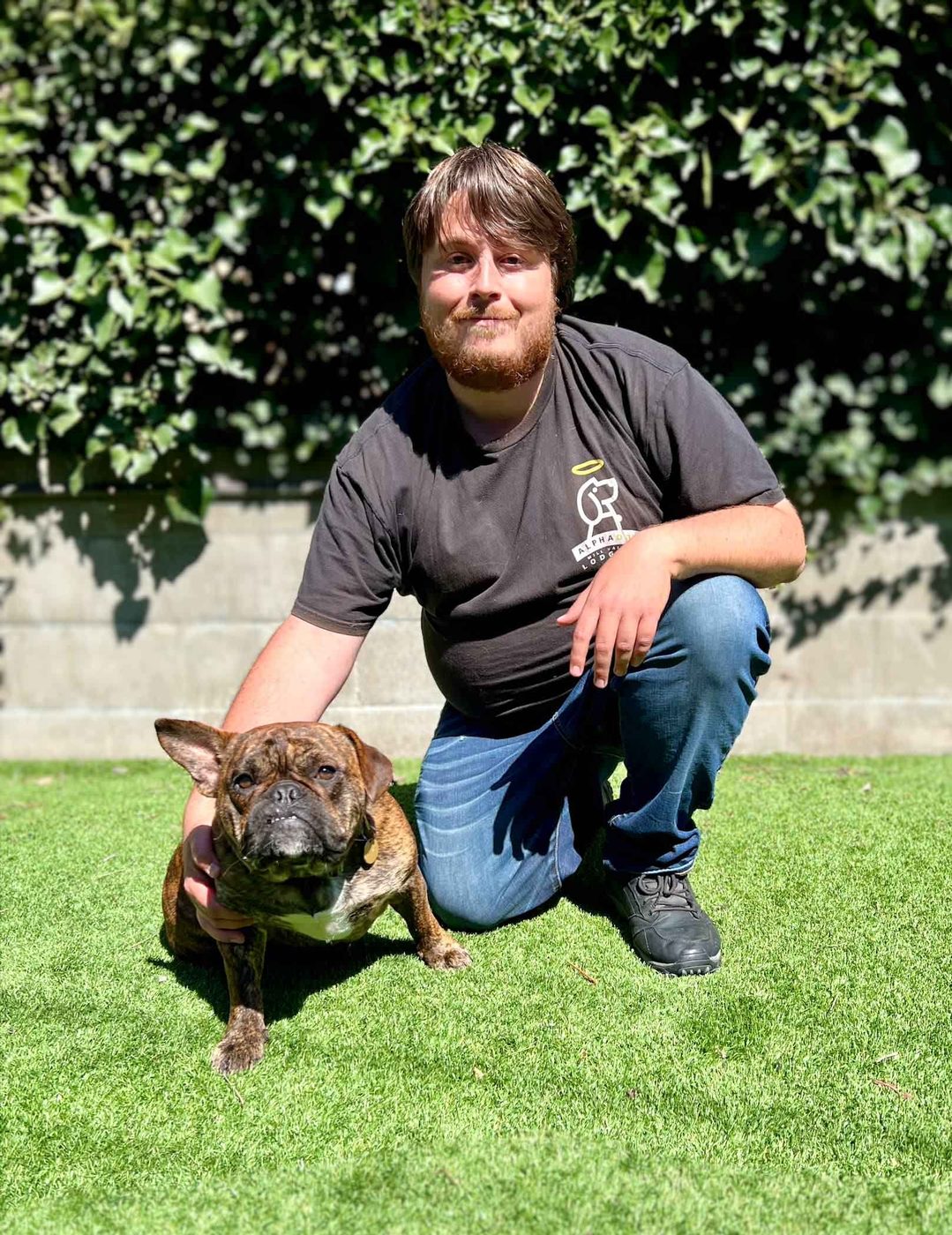 An AlphaDog team member with a dog in the yard