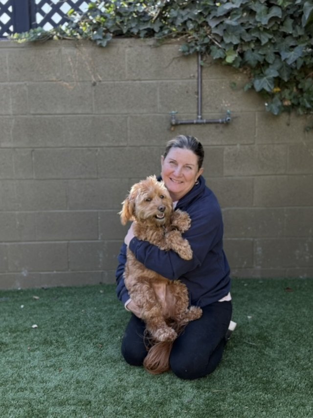 An AlphaDog team member with a dog in the yard